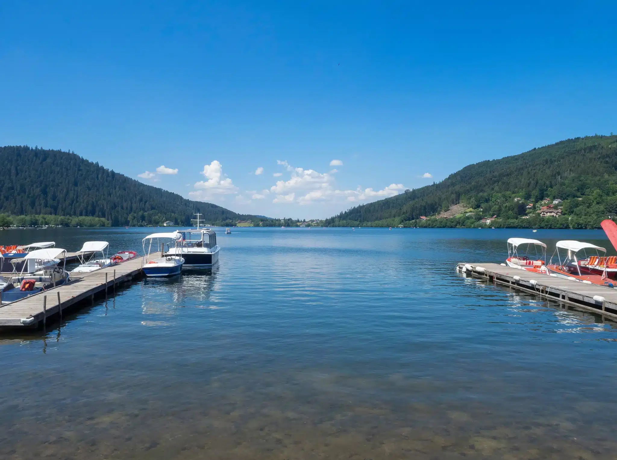 Holzsteg mit Booten und Campern am Ufer des Sees von Gérardmer in den Vogesen.